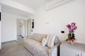 A modern living room with a patterned sofa, a white cabinet, and a potted orchid plant.