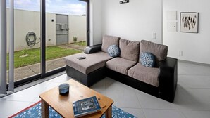 Una sala moderna con un sofá seccional, una mesa de centro y un suelo de vidrio corredera que da a un patio.