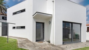 Un edificio moderno blanco con puerta de garaje, una entrada pequeña y un amplio ventanal corredera.