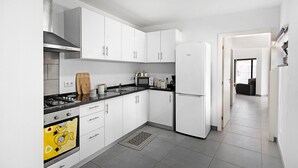 Una cocina moderna con armarios blancos, un microondas, una estufa y un refrigerador.
