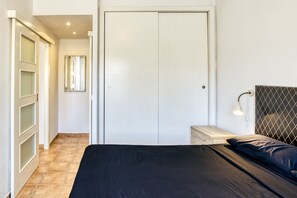 Une chambre à coucher comprenant un lit, une table de chevet, une lampe, une armoire et un miroir.