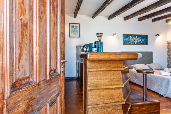 Une porte en bois, un lit avec une tête de lit, une machine à café et un tableau accroché au mur.