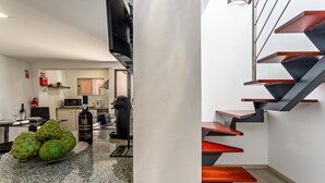 Una cocina moderna con encimera de granito, zona de comedor y una escalera original con peldaños de madera y barandillas metálicas.