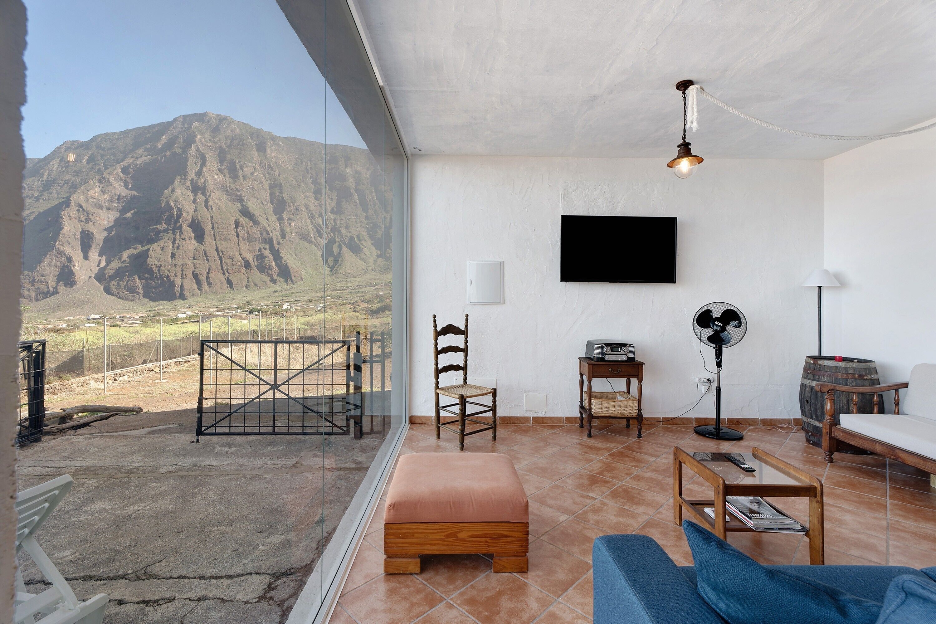 A living room with a mountain view, a television, a fan, and a wooden table.