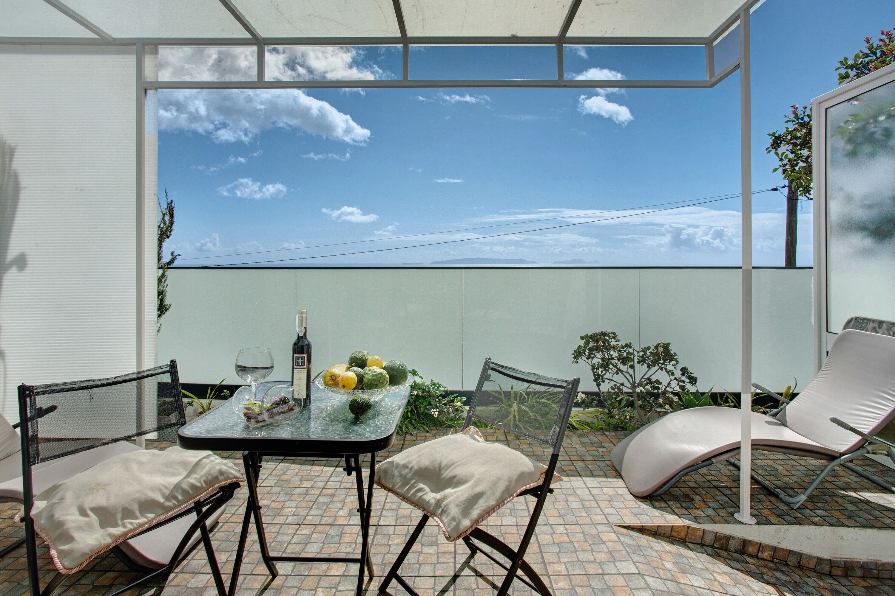A patio with a table, chairs, and a glass partition.