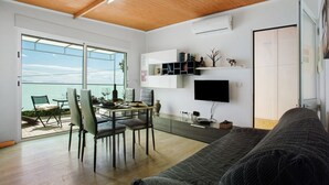 Ein modernes Wohnzimmer mit Essbereich, einem an der Wand montierten Fernseher und einer Glastür zum Balkon.