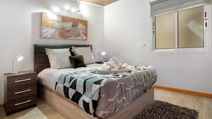 Ein Schlafzimmer mit einem Bett, Nachttischen, einem Gemälde und einer Klimaanlage.