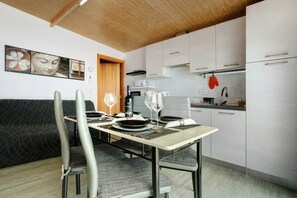 Uma cozinha moderna com armários brancos, uma mesa de jantar posta com pratos, copos e talheres.