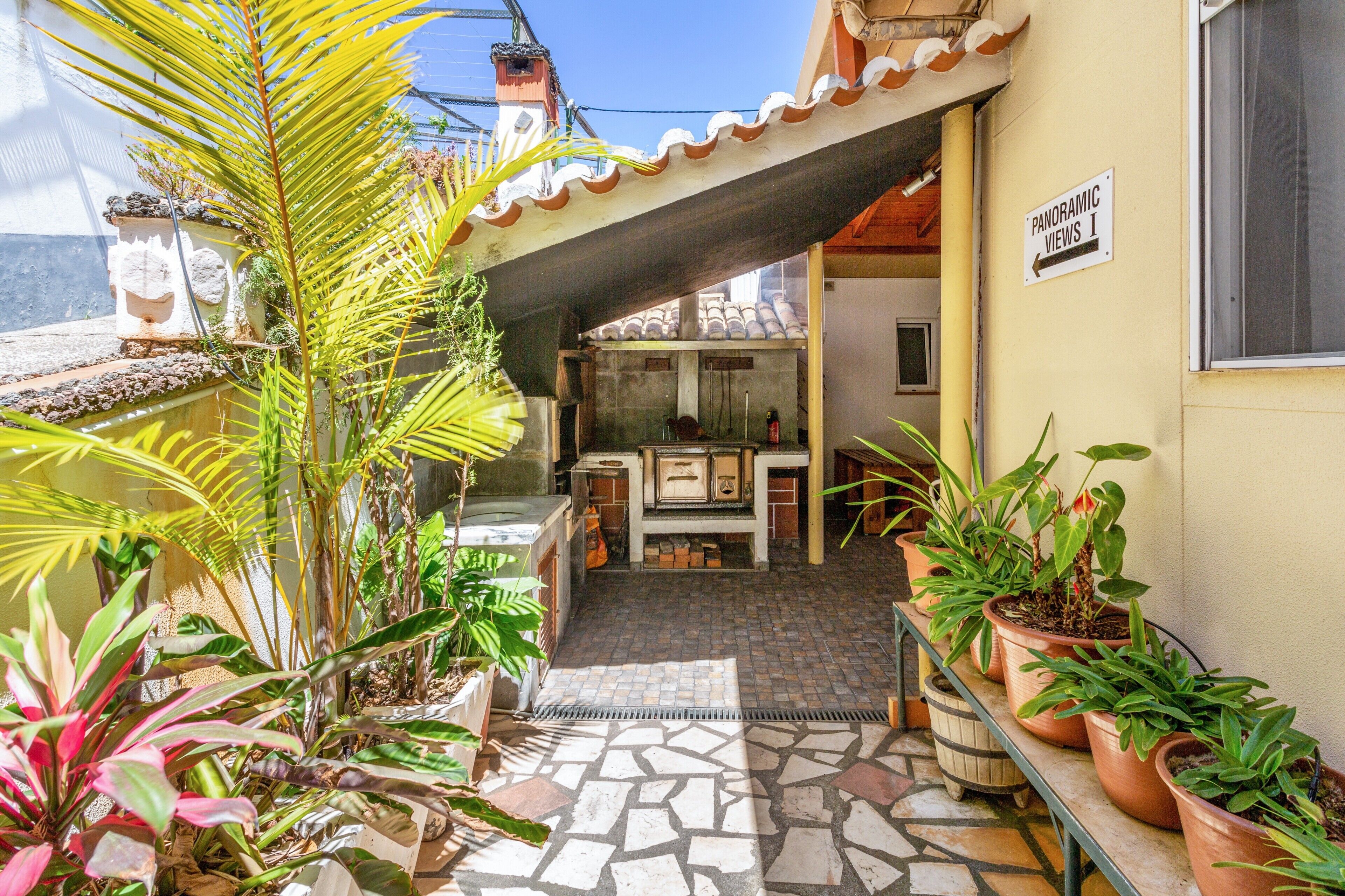 A patio area with potted plants, a stone-tiled floor, and a sign indicating 'Panoramic Views.'