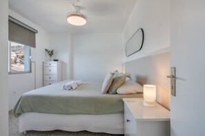 Une chambre à coucher avec un lit, une table de chevet, une lampe et une fenêtre donnant sur un beau paysage.