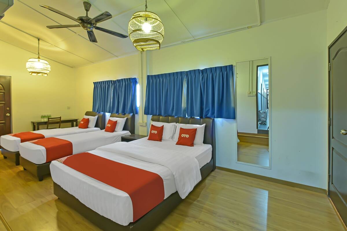 A hotel room with two beds, a ceiling fan, a chandelier, and a large mirror.