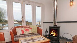 A cozy room with a fireplace, a sofa with plaid cushions, and a wooden table. - 12 Manleigh Park (Ilfracombe)