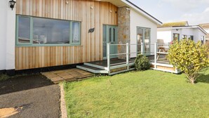 A modern house with a wooden facade, large windows, and a small porch. - Tinkers Patch (Tyn-y-Gongl)
