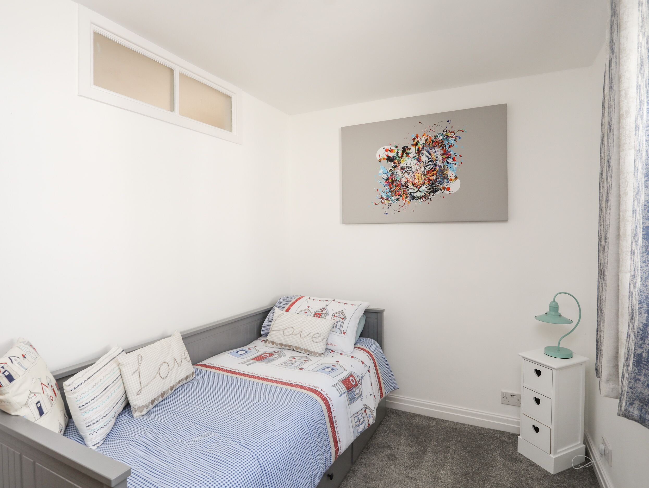 A bedroom with a bed, a nightstand, a lamp, and a wall art piece.