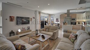 Ein modernes Wohnzimmer mit Flachbildfernseher, bequemen Sofas, einem Couchtisch und einer Küchenzeile mit Geräte.