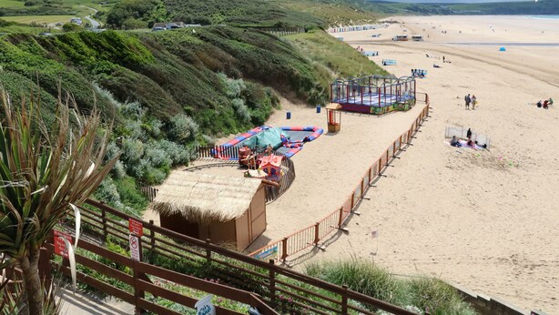 A beach with a fenced area containing a small building and a play structure. - 14 Manleigh Park (Ilfracombe)