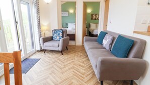 A modern living room with a grey sofa, a matching armchair, and a wooden floor. - 14 Manleigh Park (Ilfracombe)