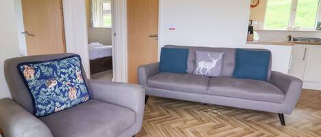 A living room with a grey sofa, a grey armchair, and a patterned throw pillow.