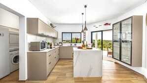 Cozinha moderna com ilha central, eletrodomésticos embutidos e uma ampla janela com vista para o exterior.