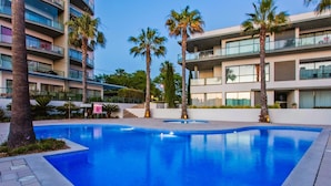 Une piscine entourée de palmiers et de bâtiments modernes.
