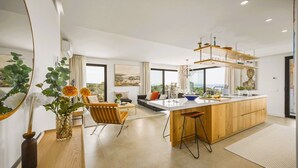 Une cuisine moderne dotée d’un îlot central, de grandes fenêtres et offrant une vue sur la mer.