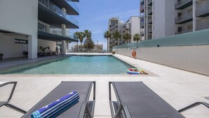 Ein moderner Poolbereich mit Liegestühlen und freiem Blick auf die umliegenden Gebäude.