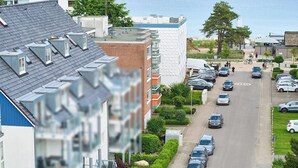 A residential street with multiple parked cars, a pedestrian pathway, and a building with a unique textured facade. - Hansa-residenz II Appartement 9 (Scharbeutz)