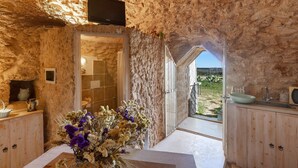 Un interior rústico de piedra con un tocador de madera, un lavamanos y un arreglo floral.