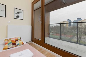 Een hotelkamer met een groot raam, een bed met een kleurrijk kussen, en uitzicht op de stadsgezicht.