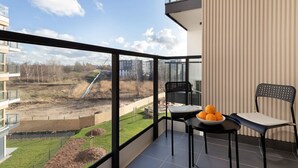 A balcony with a view of a construction site, a table with a bowl of oranges, and two chairs. - Comfortable Apartment in Gdansk | Parking | Balcony | AC (Gdańsk)