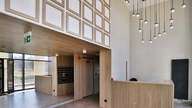 A modern reception area with a wooden reception desk, a glass door entrance, and a ceiling with hanging pendant lights. - Comfortable Apartment in Gdansk | Parking | Balcony | AC (Gdańsk)