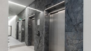 A modern elevator area with marble walls and a clean, tiled floor. - Modern Studio with Balcony | Parking | Close to EXPO XXI (Warszawa)
