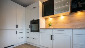 Une cuisine moderne avec des meubles blancs, un four encastré et un plan de travail en bois.