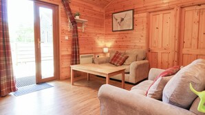 A wooden cabin interior with a sofa, a table, and a lamp. - 1 Manleigh Park (Ilfracombe)