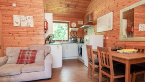 A cozy cabin interior with a living area, dining table, and kitchen. - 1 Manleigh Park (Ilfracombe)