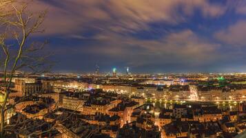 A panoramic view of a cityscape at night with illuminated buildings and a river.