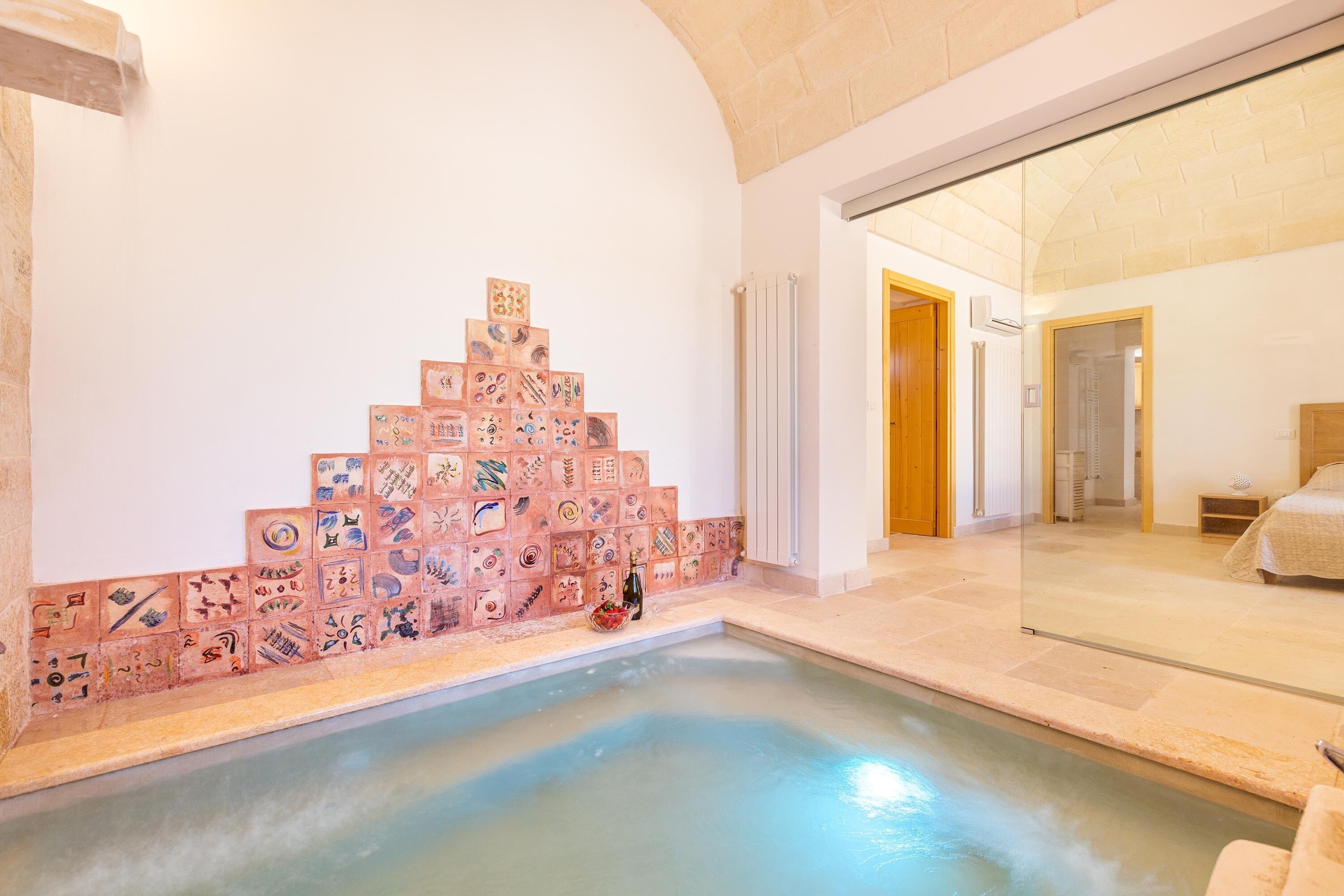 A spa area with a tiled wall and a hot tub.