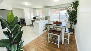 Una cocina moderna con armarios blancos, una isla central y una zona de comedor con bancos.