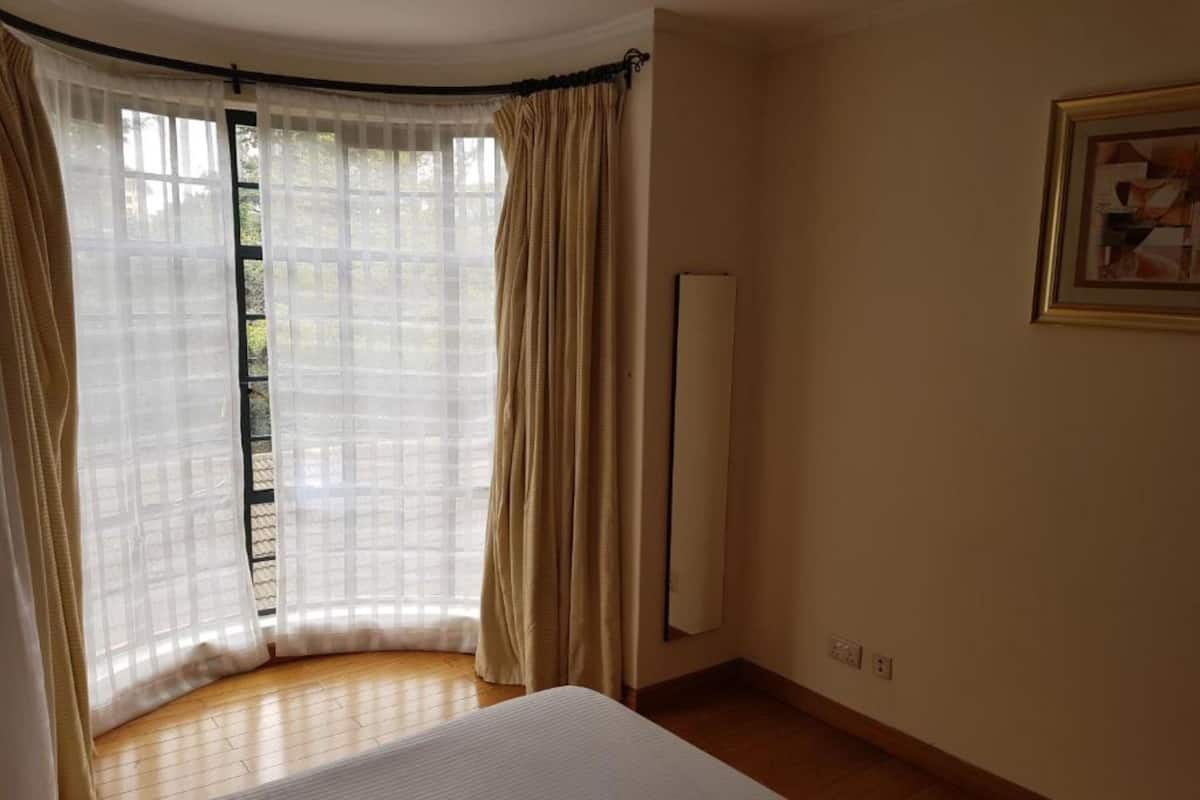 Ein Schlafzimmer mit einem großen Bett, einem Heizkörper und einem mit Vorhängen versehenen Fenster.