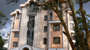 A multi-story building with a symmetrical facade, large windows, and a central entrance. - Natural Oak Apartments (Nairobi)