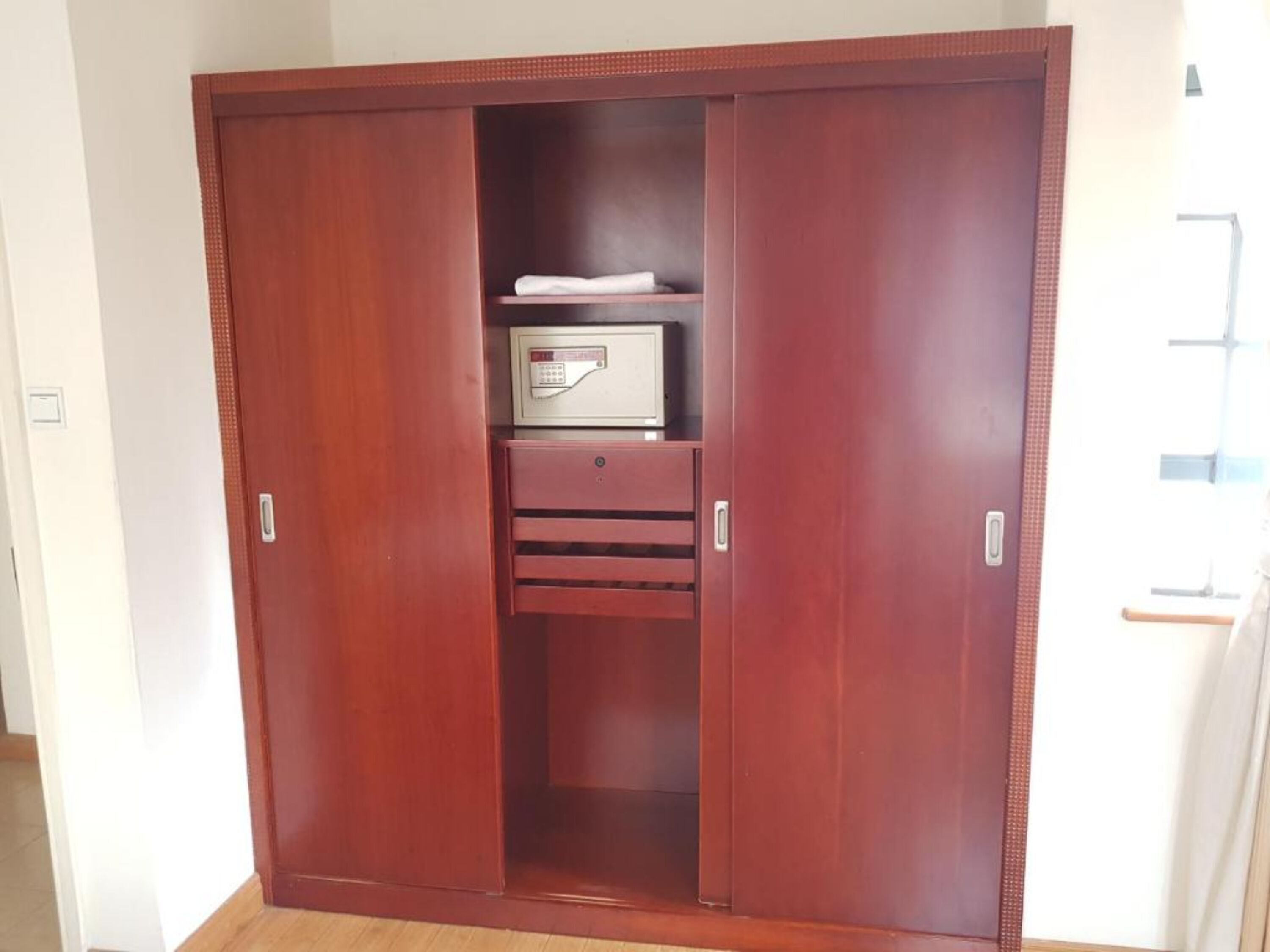 Une armoire en bois dotée d’un coffre-fort intégré, d’une étagère et d’un tiroir.