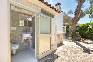 A bathroom with a toilet, sink, and glass shower door. - 3229 Trullo Mimosa by Perle di Puglia (San Michele Salentino)