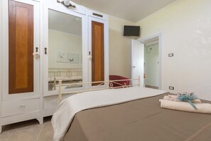 A bedroom with a bed, a wardrobe, a mirror, and a television. - 3229 Trullo Mimosa by Perle di Puglia (San Michele Salentino)