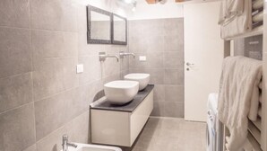 Un bagno moderno con soffitto in legno, uno specchio grande e un portasciutto integrato.