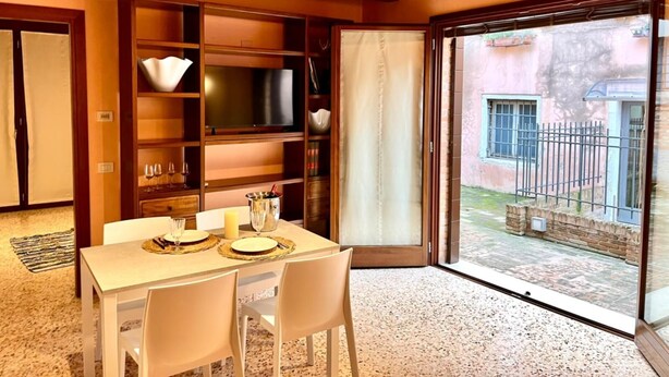 Zona de menjador amb taula preparada per a dues persones, televisió i finestra gran amb vista a l'exterior.