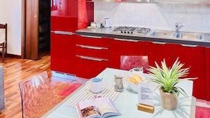 Una cocina moderna con gabinetes rojos, una estufa a gas, un microondas y un extractor de acero inoxidable.