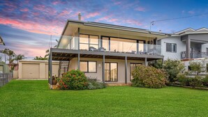 A modern two-story house with a covered patio, a garage, and a well-maintained lawn. - Tanapaser – spacious centrally located home with fireplace (Currarong)
