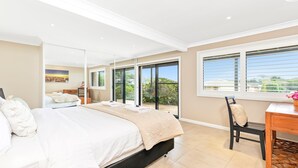 Une chambre avec un lit, un bureau et une vue sur l’extérieur, accessible par une porte-fenêtre coulissante.