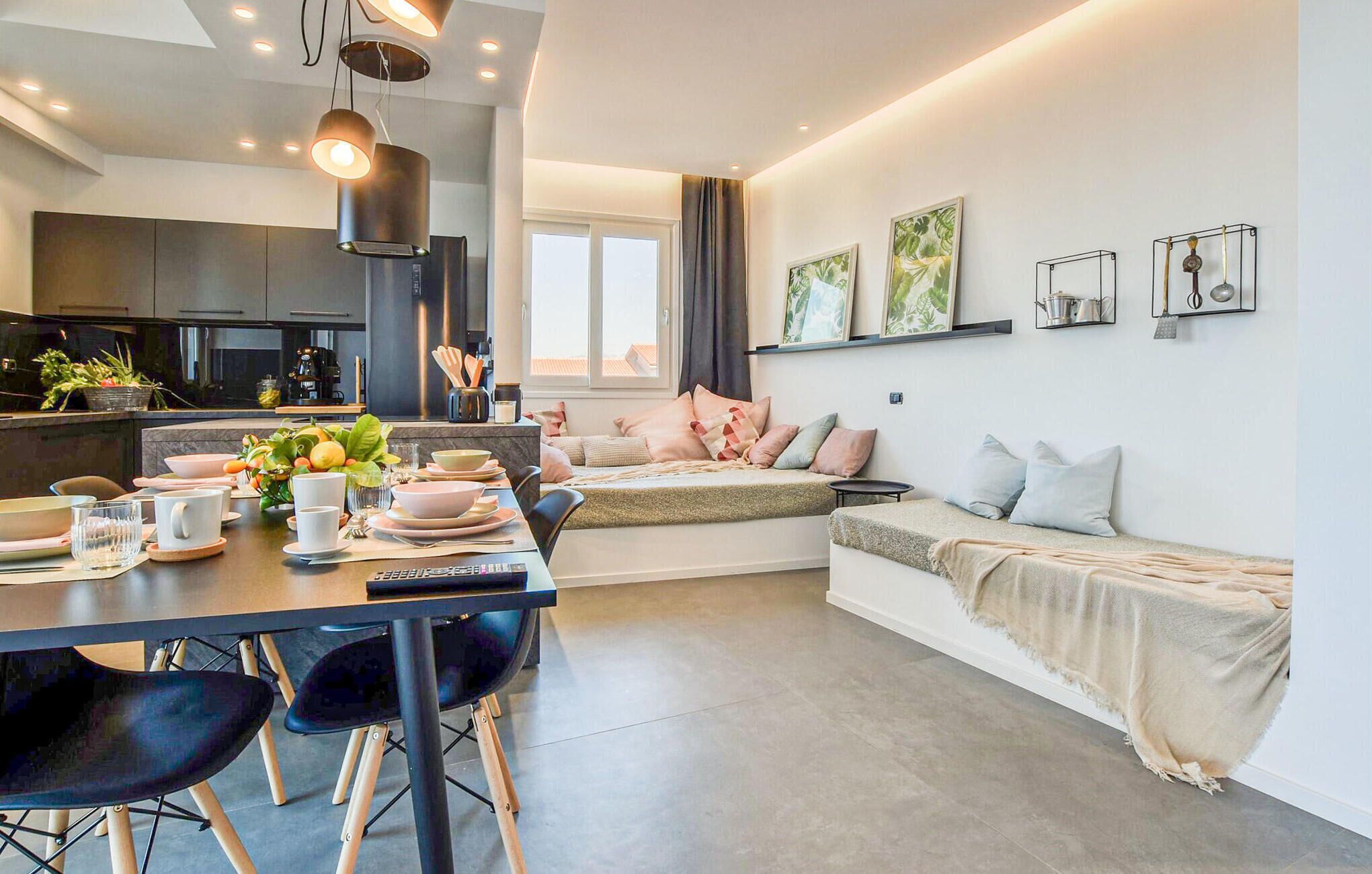 Een moderne keuken met donkere kastjes en een eethoek met een tafel voor vier personen.