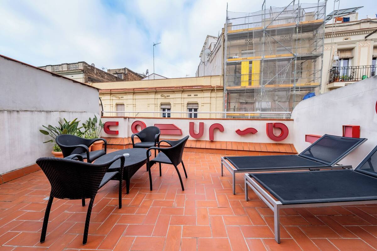 A rooftop terrace with outdoor seating and a large red sign.